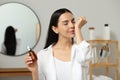 Young woman smelling essential oil on wrist indoors Royalty Free Stock Photo