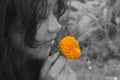 A young woman smelling orange marigold flower with a smiling face, in black and white background. Royalty Free Stock Photo