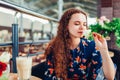 Young woman smelling rose in shopping center cafe while drinking coffee Royalty Free Stock Photo