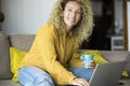 Young woman smile and work on laptop at home sitting on the sofa. Happy adult female people using computer and internet connection Royalty Free Stock Photo