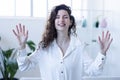 young woman smiles with both hands up and signs, female at home cheerful smiles at the camera