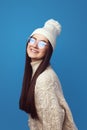 Young woman smiles at camera, wears white hat and knitted white oversized sweater