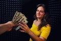 A young woman smiles getting money for work in a recording Studio. The moment of transfer of dollars from hand to hand for the