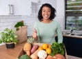 A young woman smiles and gives thumbs up to delivery of fresh fruit and veg box Royalty Free Stock Photo