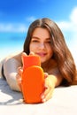 .Young woman smiling on beach and holding sunscreen bottle in her hands