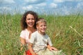 Young woman and smiling boy sitting on meadow Royalty Free Stock Photo