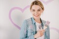 Young woman smiling at camera while holding pink paintbrush Royalty Free Stock Photo