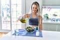 Young woman smiling confident pouring oil on salad at kitchen Royalty Free Stock Photo