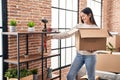 Young woman smiling confident unboxing fragile cardboard box at new home Royalty Free Stock Photo