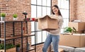 Young woman smiling confident unboxing fragile cardboard box at new home Royalty Free Stock Photo