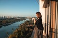 Young woman smiling and drinking some beverage and looking out from balcony