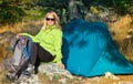 Young Woman with Smiling Face Hiker sitting with backpack and Tent Camping Outdoor