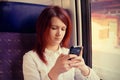 Young woman smiling feeling relaxed and talking to mobile phone traveling near train window