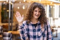 Young woman smiling friendly at camera, waving hands hello, hi, greeting or goodbye in city street Royalty Free Stock Photo