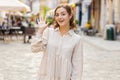 Young woman smiling friendly at camera, waving hands hello, hi, greeting or goodbye in city street Royalty Free Stock Photo