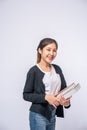 Young woman smiling happily in a black shirt and jeans, holding a book and smiling happily Royalty Free Stock Photo