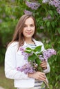 Young beautiful girl stands near the bushes of blooming lilac Royalty Free Stock Photo
