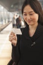 Young Woman Smiling and Looking At Train Ticket on Railroad Platform Royalty Free Stock Photo