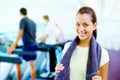 Young woman smiling. Portrait of young smiling woman holding water bottle and towel with people working out in Royalty Free Stock Photo