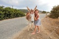 Young woman smiling, posing with wild donkey, giving him hug. These animals roam freely in Karpass region of Northern Cyprus