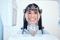 Young woman smiling and standing with her head in a panoramic dental xray machine. Getting her mouth checked at a visit Royalty Free Stock Photo