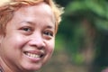 A young woman smiling to camera with green bokeh background.