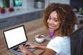 Young woman smiling while using laptop in kitchen Royalty Free Stock Photo