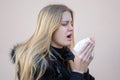 Woman sneezing in winter in black jacket