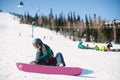 Sport.Young woman with a snowboard sitting on a snowy slope. Royalty Free Stock Photo