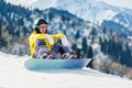 Young woman snowboarder sitting in the snow and exploring the slope before the descent Royalty Free Stock Photo