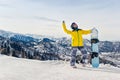 Young woman snowboarder in a yellow jacket and black helmet on the background of snowy mountains Royalty Free Stock Photo