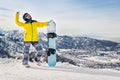 Young woman snowboarder in a yellow jacket and black helmet on the background of snowy mountains Royalty Free Stock Photo