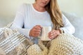 Young woman snuggled up in a blanket holding a hot cup of tea Royalty Free Stock Photo