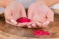 Young woman soaking hands in water with red flower and natural manicure