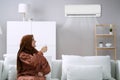 Young Woman Operating Air Conditioner Royalty Free Stock Photo