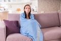 Young Woman on Sofa Wrapped in Blue Blanket Royalty Free Stock Photo