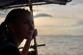 Young woman, solo traveler on boat at sea admires sunset