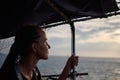 Young woman, solo traveler on boat at sea admires sunset