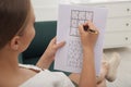 Young woman solving sudoku puzzle on sofa, closeup Royalty Free Stock Photo