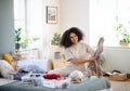 Young woman sorting clothing indoors at home, charity donation concept.