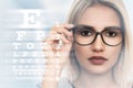 Young woman with spectacles on eyesight test chart background Royalty Free Stock Photo