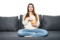 Young woman spends his free time watching TV on the couch at home, munching chips.