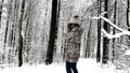 Young woman is spinning and snow falls from the branches on her