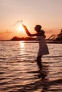 A young woman splashes water. Photo of a slender, beautiful, happy blonde in a summer dress and a straw hat standing in Royalty Free Stock Photo