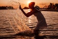 A young woman splashes water. Silhouette photo of a beautiful happy blonde in a summer dress and a straw hat with a Royalty Free Stock Photo