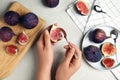 Young woman with spoon and fig at light grey marble table