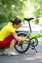 Young woman in sport clothes repairs bike in park Royalty Free Stock Photo