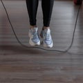 Young woman in sports black leggings in stylish sneakers do jumping rope at the gym. Girl goes in for sports in a fitness studio. Royalty Free Stock Photo