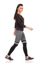 Walking Young Woman In Sports Clothes Is Looking At Camera And Smiling. Side View. Royalty Free Stock Photo