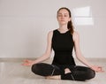Young woman in sports clothes meditating in lotus position while doing yoga at home Royalty Free Stock Photo
